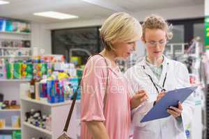 Pharmacist writing prescription with her customer