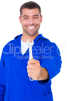 Smiling male mechanic showing spanner