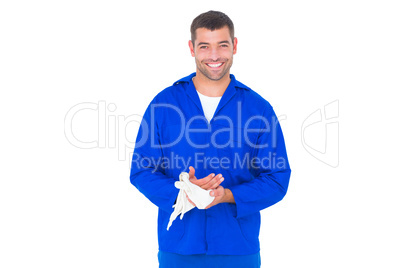 Smiling mechanic wiping hands with cloth