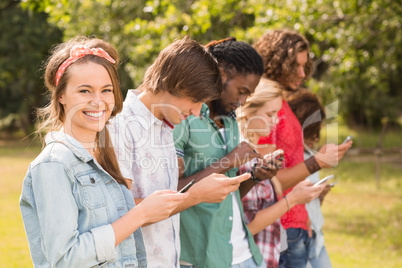 Happy friends in the park using their phones