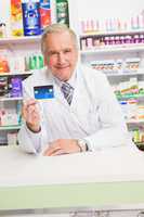 Smiling senior pharmacist holding credit card