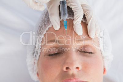 Woman receiving botox injection on her forehead