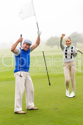 Golfing couple cheering on the putting green