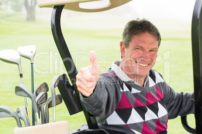 Happy golfer driving his golf buggy smiling at camera