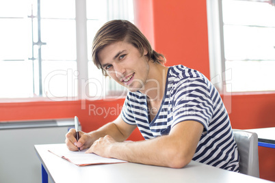 Male student writing notes in classroom