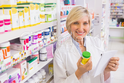 Smiling pharmacist holding prescription and medicine