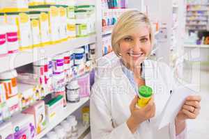 Smiling pharmacist holding prescription and medicine
