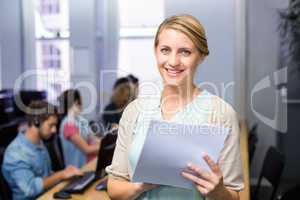 Female teacher holding document in computer class