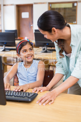 Cute pupil in computer class with teacher