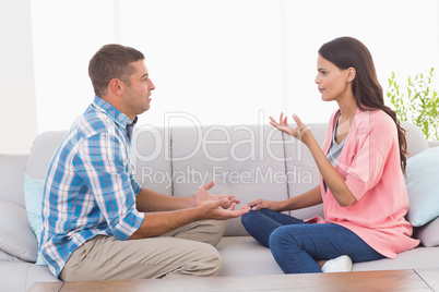 Couple arguing while sitting on sofa