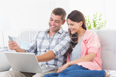 Couple shopping online through laptop using credit card