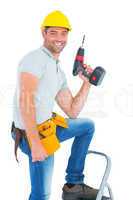 Confident handyman holding power drill while climbing ladder