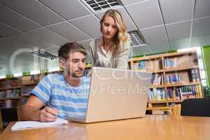 Student getting help from tutor in library