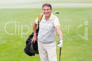 Handsome golfer standing with golf bag