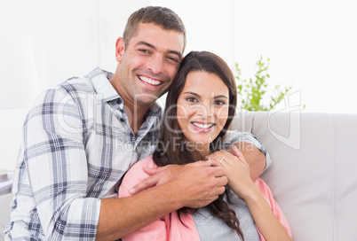 Happy man embracing woman on sofa