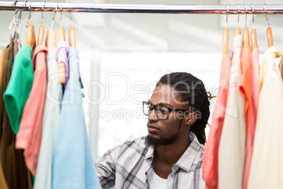 Male fashion designer looking at rack of clothes