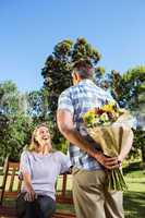 Man surprising his girlfriend with a bouquet in the park