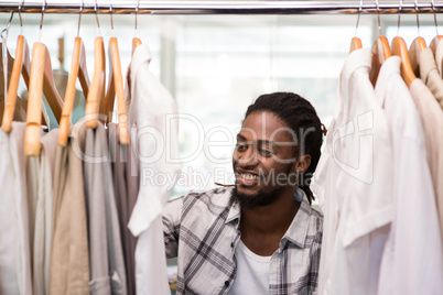 Male fashion designer looking at rack of clothes