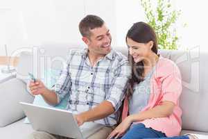 Couple shopping online on laptop using credit card