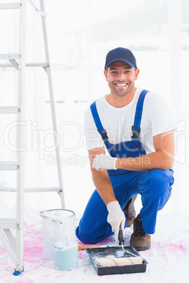 Portrait of smiling handyman using paint roller in tray