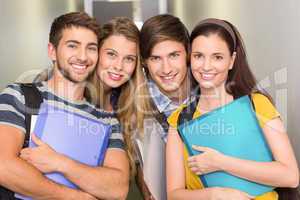 Happy students holding folders at college corridor