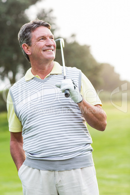 Golfer standing and swinging his club smiling at camera