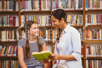 Teacher and girl reading book in library