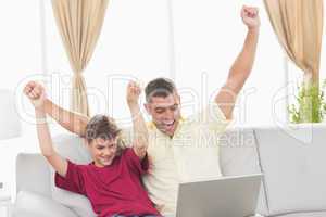 Father and son with arms raised celebrating success