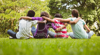 Children sitting with arms around at park