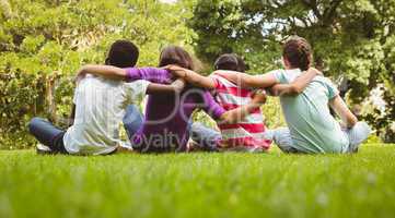 Children sitting with arms around at park