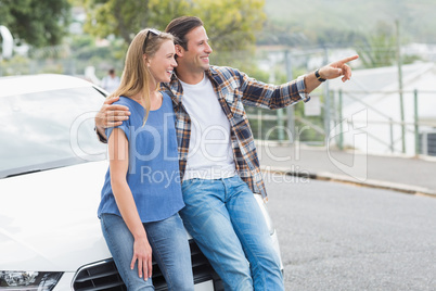 Smiling couple leaning on the bonnet