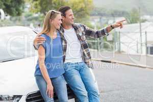 Smiling couple leaning on the bonnet