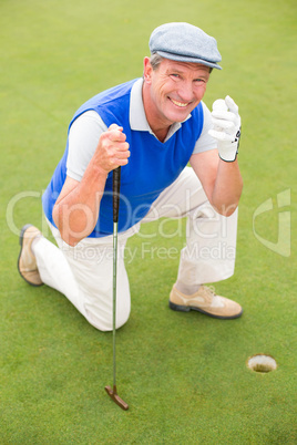 Smiling golfer kneeling on the putting green