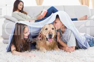 Siblings with dog under blanket