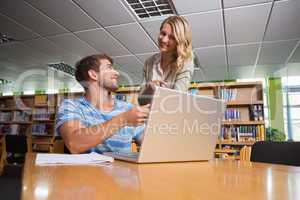 Student getting help from tutor in library