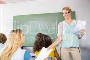 Teacher handing paper to student in class