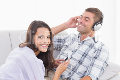 Happy woman playing music for man on mobile phone