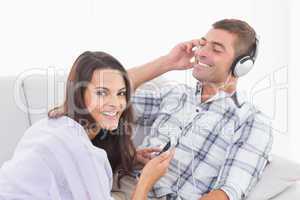 Happy woman playing music for man on mobile phone