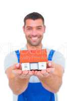 Portrait of happy handyman holding house model
