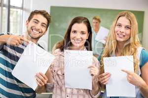 Portrait of happy students pointing at papers