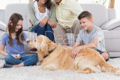 Siblings stroking dog while parents sitting on sofa