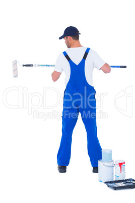Handyman in overalls using paint roller on white background