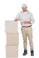 Delivery man writing on clipboard while standing by stacked boxe