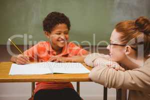 Teacher assisting boy with homework in classroom