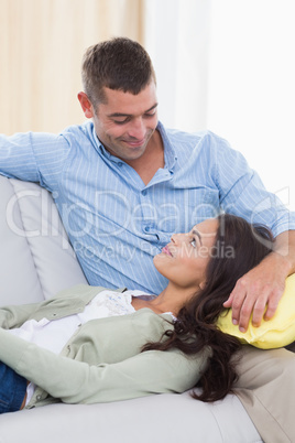 Couple looking at each other while sitting on sofa