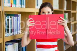 Student holding book over face