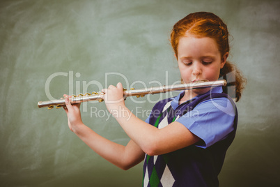 Cute little girl playing flute in classroom
