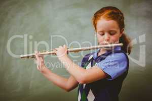 Cute little girl playing flute in classroom