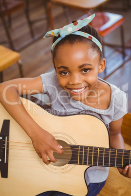 Little girl playing guitar in classroom