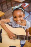 Little girl playing guitar in classroom
